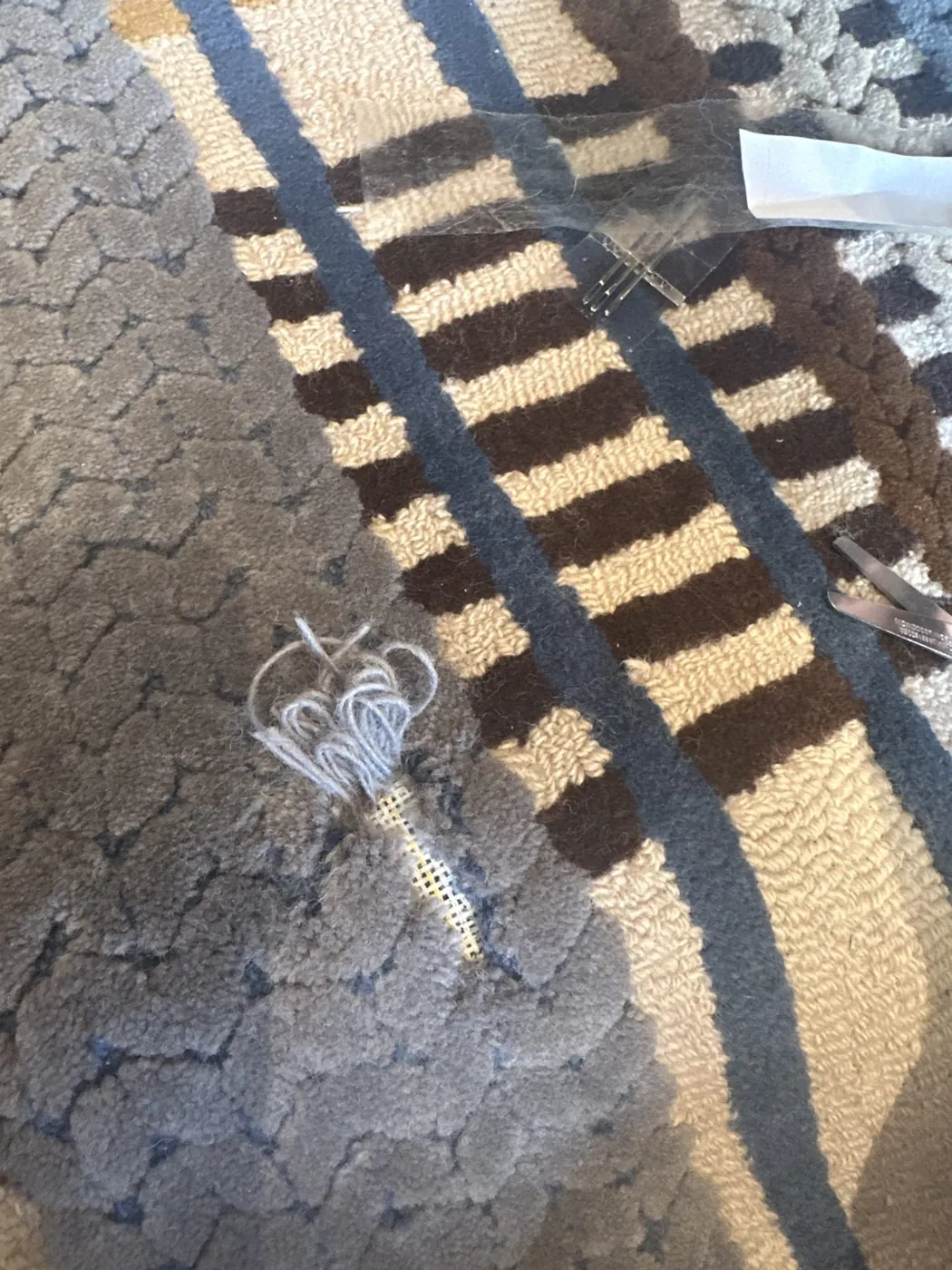Repaired section on a grey and tan rug with new threads in place