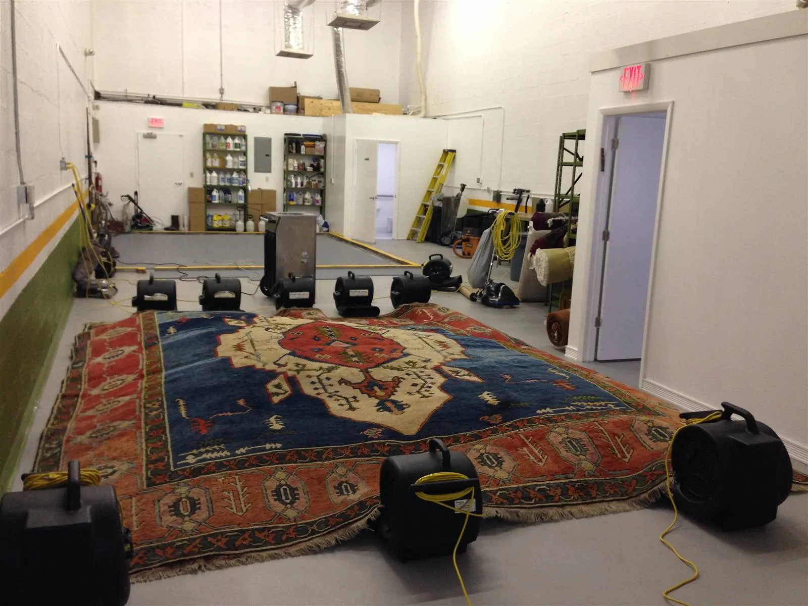 Large tribal rug drying flat with air movers in our shop